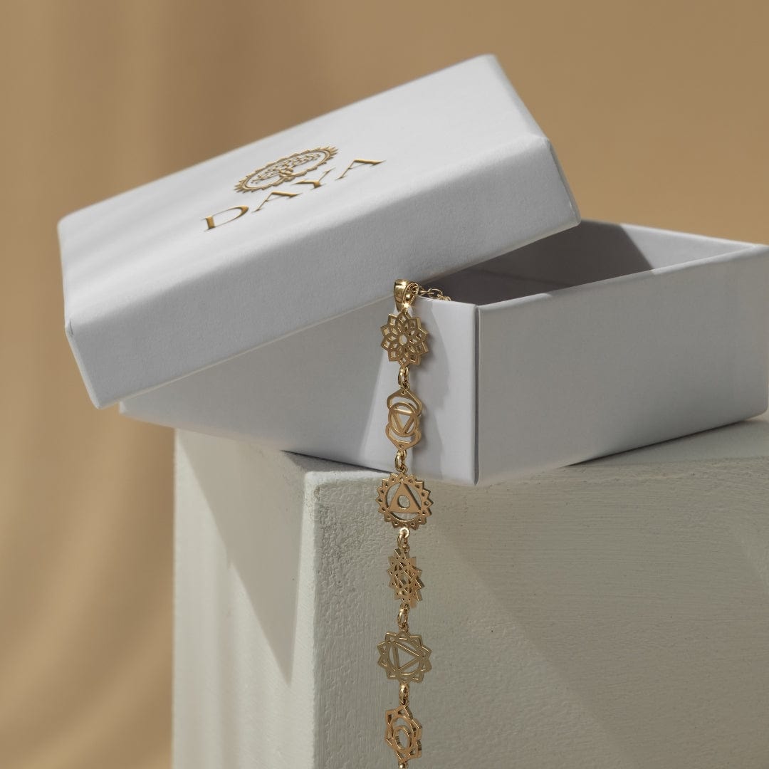 Daya gold-plated chakra necklace beside its jewelry box