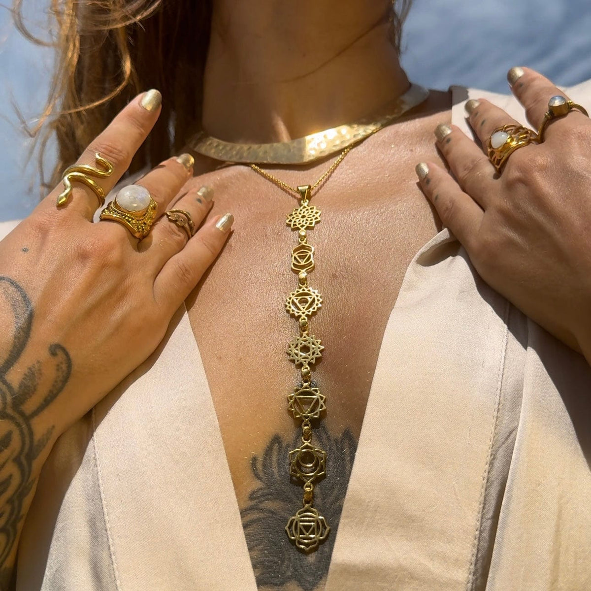 Woman wearing a long handmade Daya chakra necklace and gemstone rings